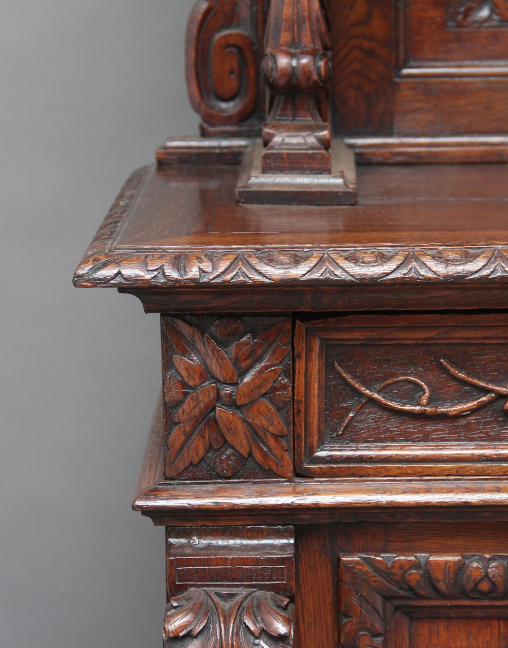 A 19th-century dark oak two-tiered buffet featuring intricate hand-carved reliefs of game, foliage, and a prominent stag head cresting. View XVI