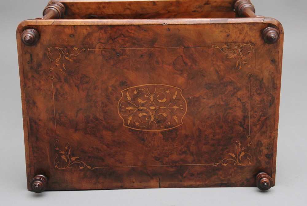 A Victorian burr walnut Canterbury featuring a flat top surface, open slatted partitions, a single base drawer, turned supports, and ceramic castors. View VIII