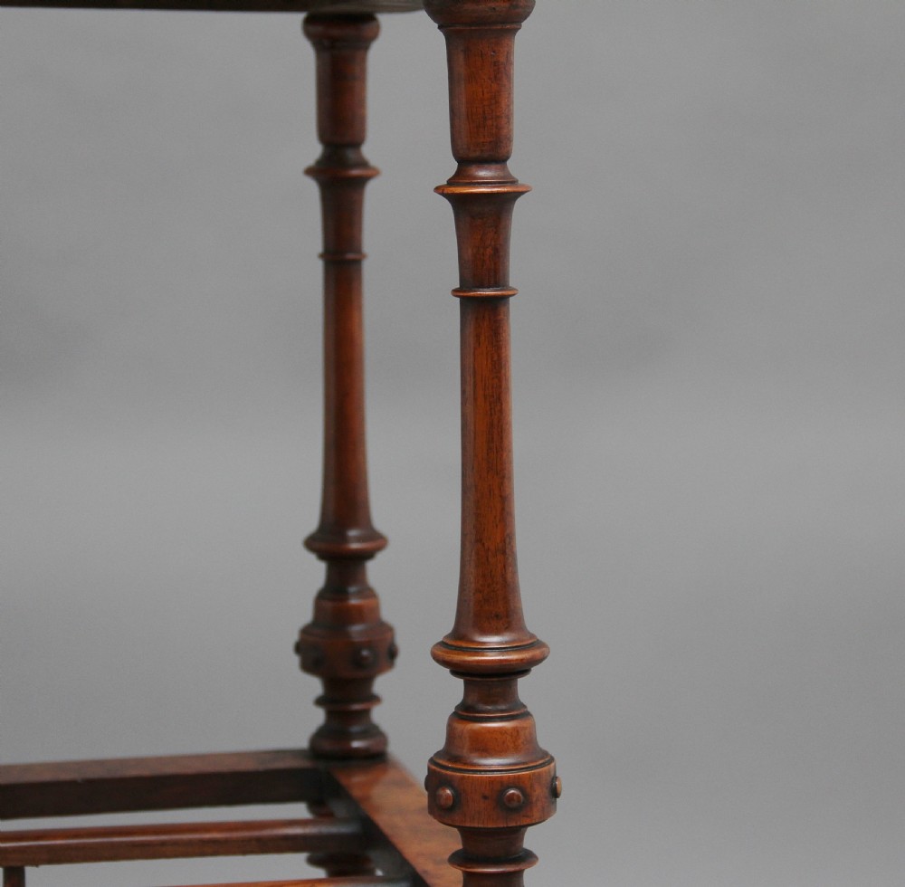 A Victorian burr walnut Canterbury featuring a flat top surface, open slatted partitions, a single base drawer, turned supports, and ceramic castors. View XII