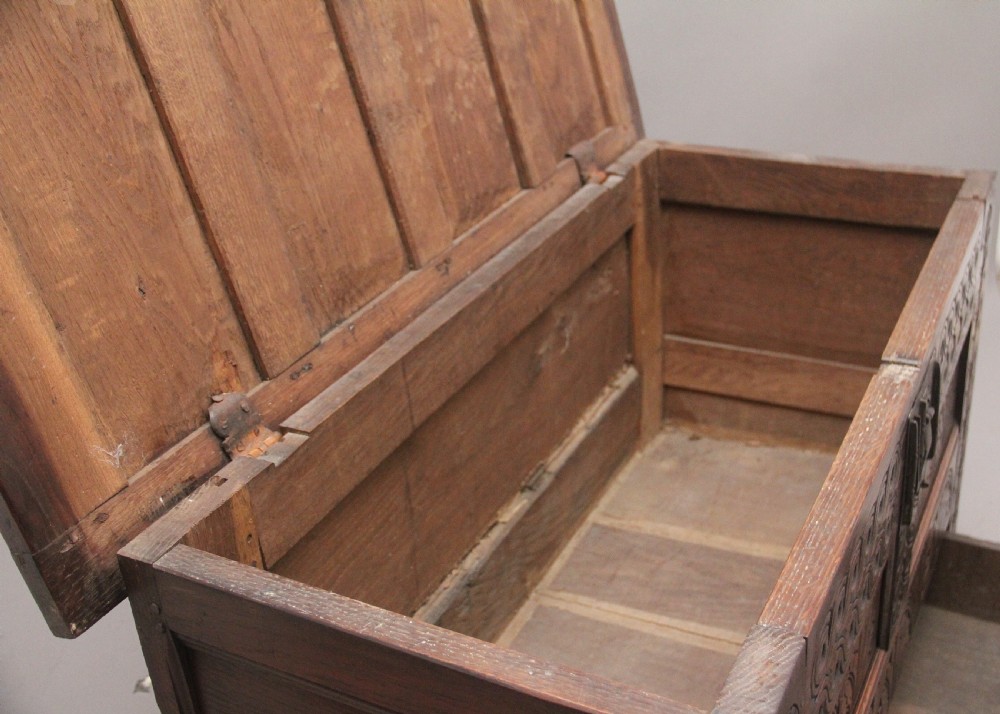An 18th-century dark carved oak mule chest featuring intricate geometric panel carvings, a central iron lockplate, and a single lower drawer. View VII