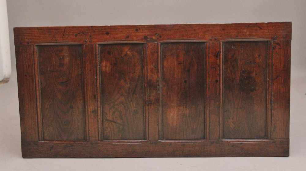 An 18th-century dark carved oak mule chest featuring intricate geometric panel carvings, a central iron lockplate, and a single lower drawer. View XI