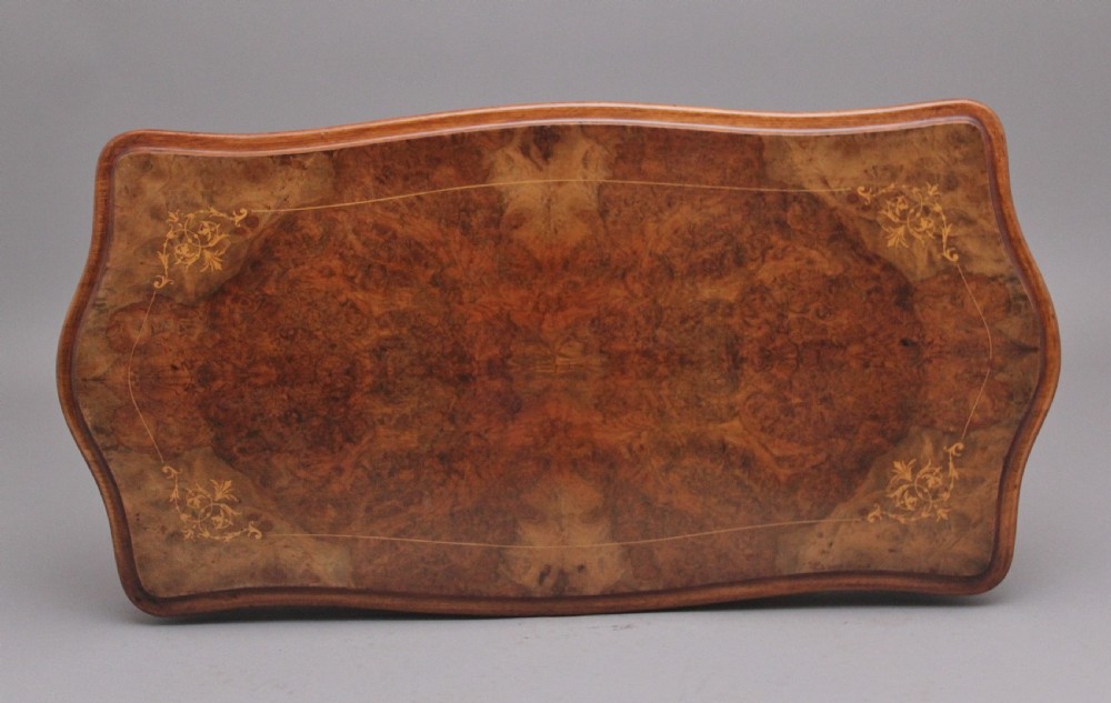 A Victorian burr walnut fold-over card table featuring a serpentine top, carved turned supports, and a stretcher base on castors. View X