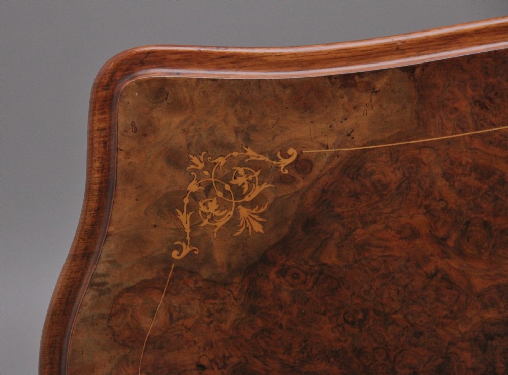 A Victorian burr walnut fold-over card table featuring a serpentine top, carved turned supports, and a stretcher base on castors. View XIII