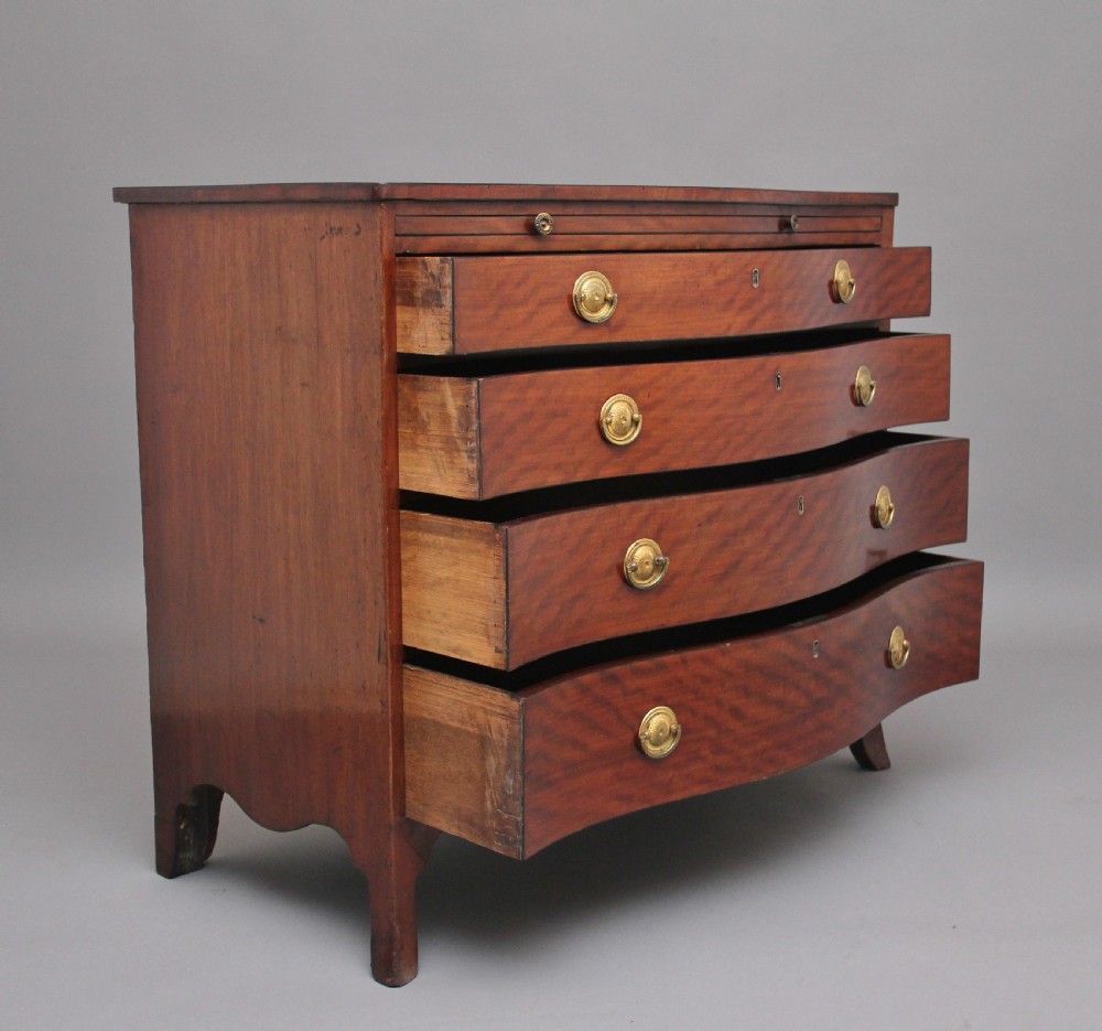An 18th-century Georgian mahogany chest of drawers with a serpentine front, four graduated drawers, circular brass ring handles, a pull-out brushing slide, and bracket feet. View II