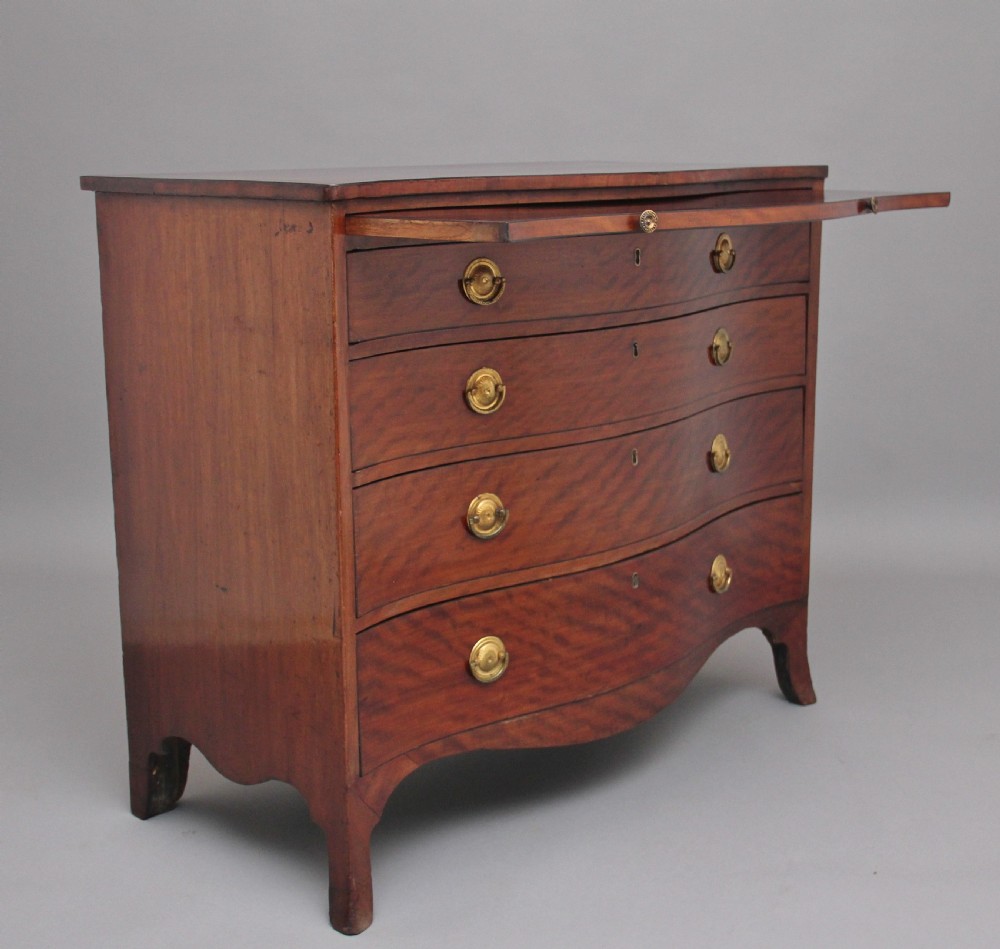 An 18th-century Georgian mahogany chest of drawers with a serpentine front, four graduated drawers, circular brass ring handles, a pull-out brushing slide, and bracket feet. View V