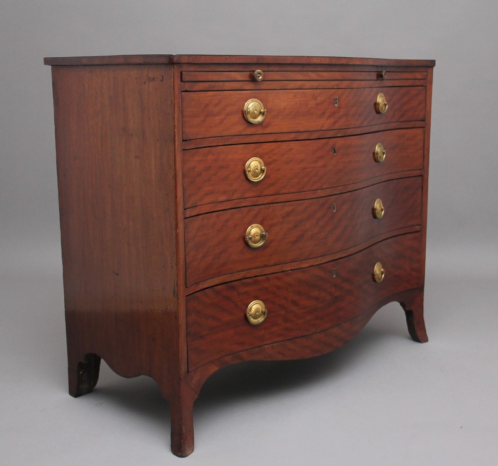 An 18th-century Georgian mahogany chest of drawers with a serpentine front, four graduated drawers, circular brass ring handles, a pull-out brushing slide, and bracket feet. View VII