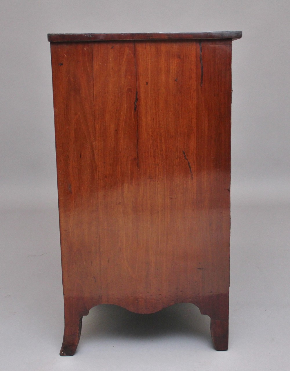 An 18th-century Georgian mahogany chest of drawers with a serpentine front, four graduated drawers, circular brass ring handles, a pull-out brushing slide, and bracket feet. View IX