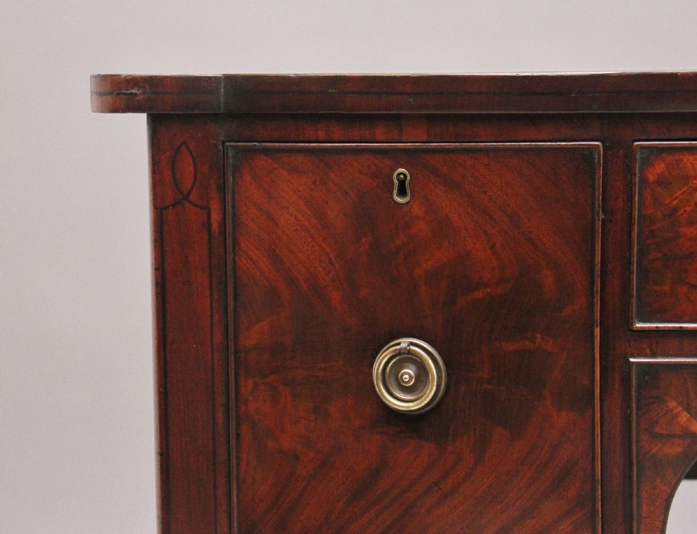 An early 19th-century bowfront mahogany sideboard with turned legs, brass ring drop handles, and central arch drawer. View III