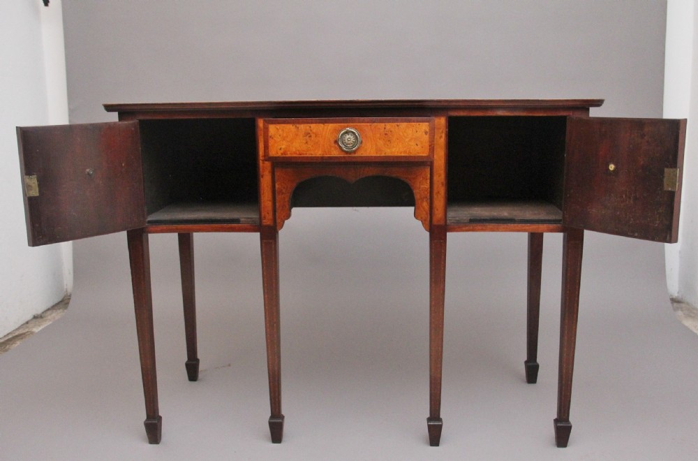 A nineteenth-century mahogany sideboard featuring burr elm veneer panels, two side cupboards, a central drawer above an arched apron, and four tapered square legs with brass ring handles. View II