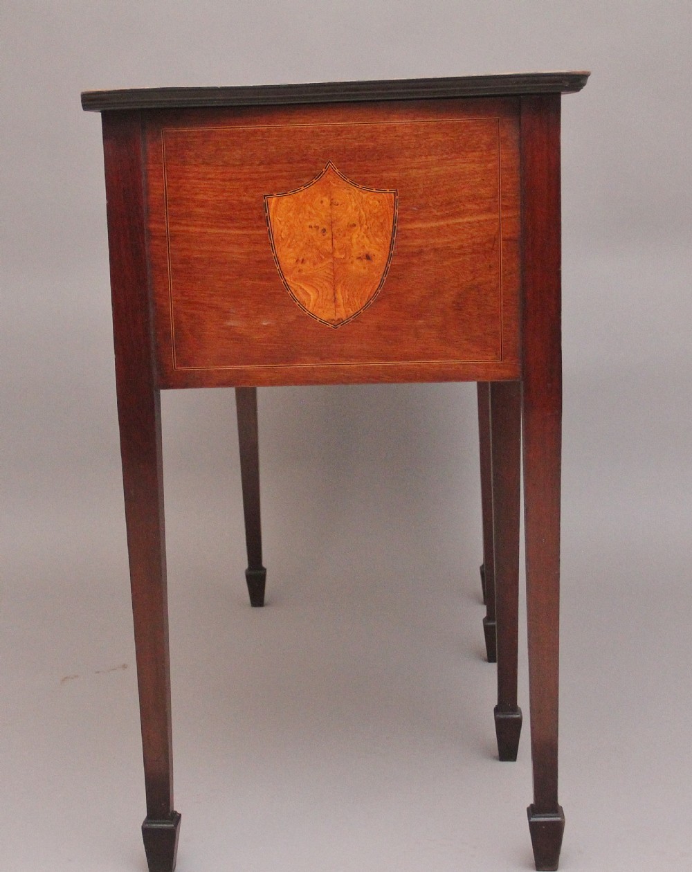 A nineteenth-century mahogany sideboard featuring burr elm veneer panels, two side cupboards, a central drawer above an arched apron, and four tapered square legs with brass ring handles. View XI