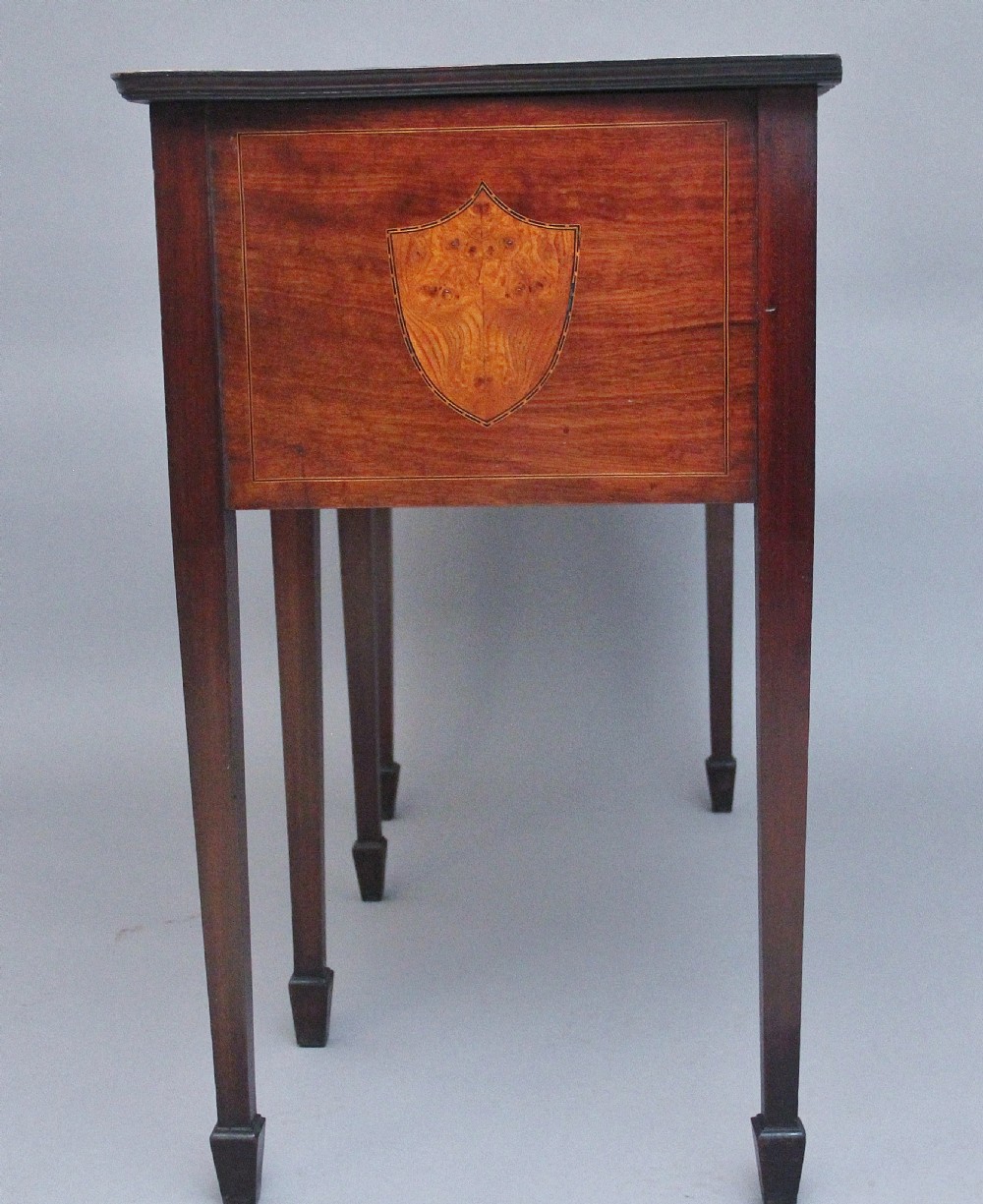 A nineteenth-century mahogany sideboard featuring burr elm veneer panels, two side cupboards, a central drawer above an arched apron, and four tapered square legs with brass ring handles. View XIV