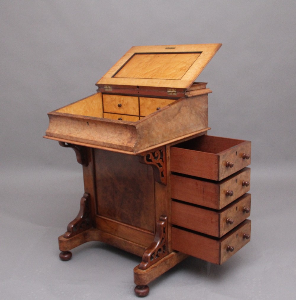 A 19th-century burr walnut Davenport desk featuring a sloped leather writing surface, side drawers with turned knobs, and carved decorative brackets. View II