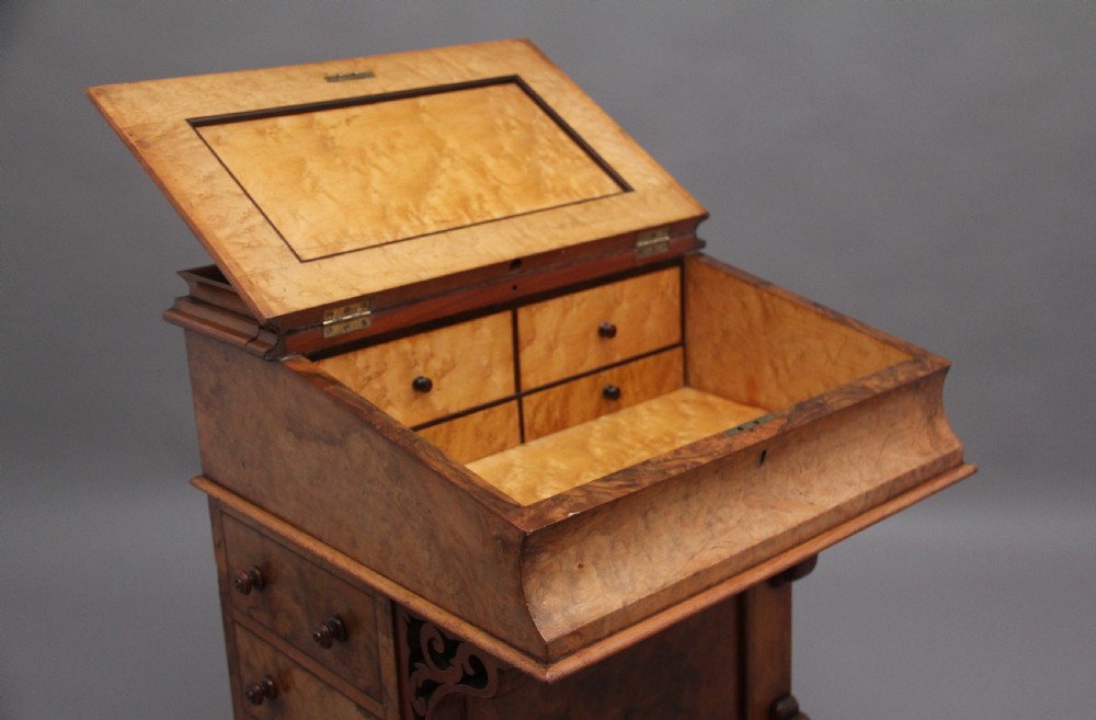 A 19th-century burr walnut Davenport desk featuring a sloped leather writing surface, side drawers with turned knobs, and carved decorative brackets. View III