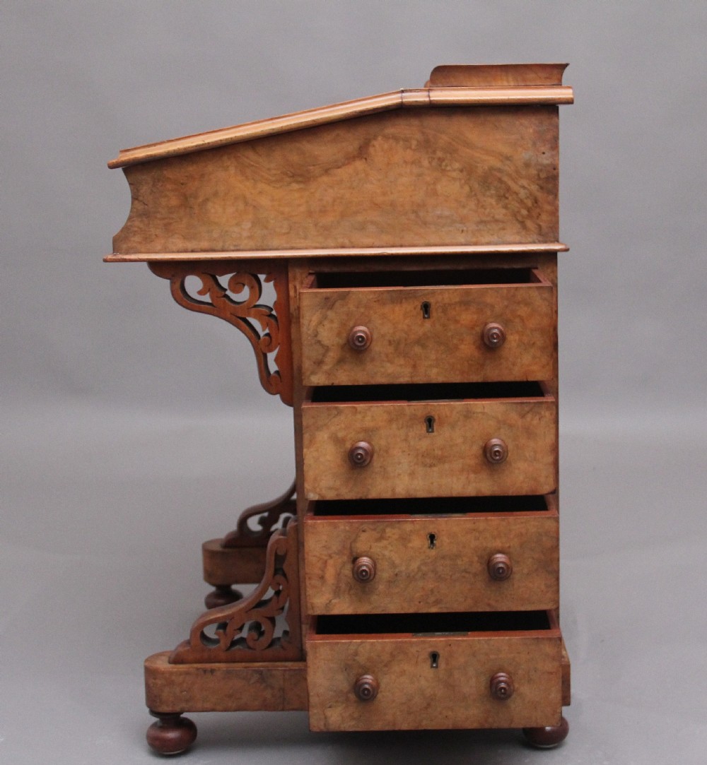 A 19th-century burr walnut Davenport desk featuring a sloped leather writing surface, side drawers with turned knobs, and carved decorative brackets. View XII