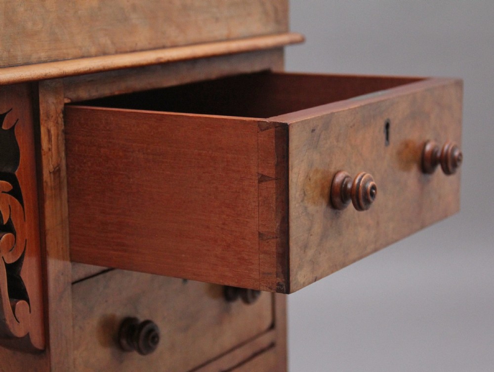 A 19th-century burr walnut Davenport desk featuring a sloped leather writing surface, side drawers with turned knobs, and carved decorative brackets. View XVI