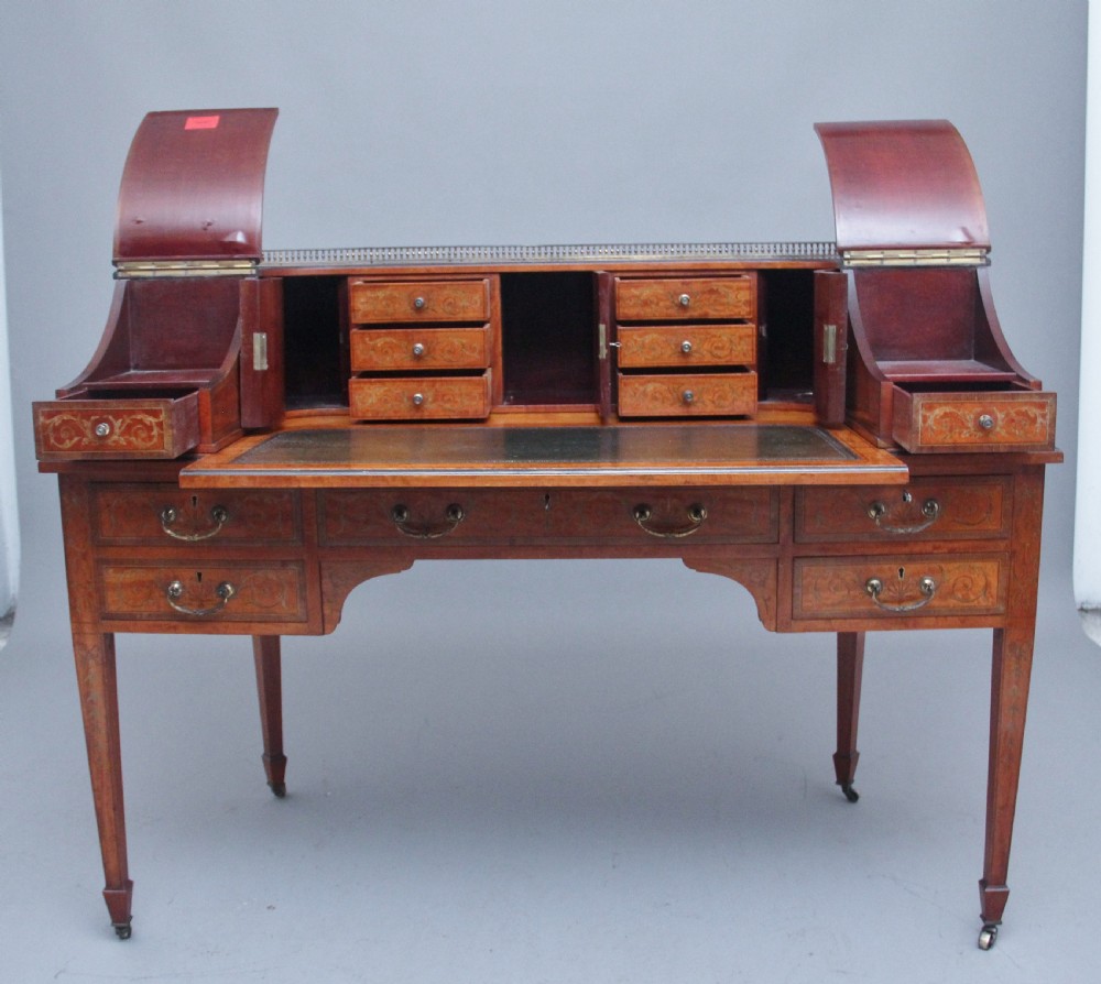 A 19th-century satinwood Carlton House writing desk featuring decorative marquetry, small drawers on a U-shaped superstructure, and tapered square legs with brass castors. View III