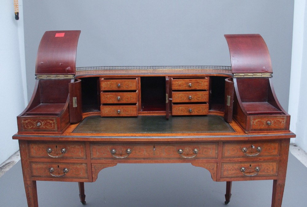 A 19th-century satinwood Carlton House writing desk featuring decorative marquetry, small drawers on a U-shaped superstructure, and tapered square legs with brass castors. View IV