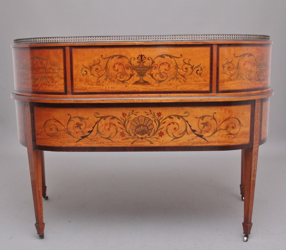A 19th-century satinwood Carlton House writing desk featuring decorative marquetry, small drawers on a U-shaped superstructure, and tapered square legs with brass castors. View VIII