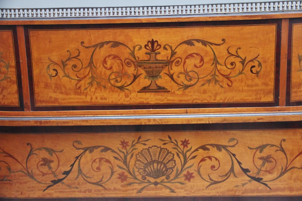 A 19th-century satinwood Carlton House writing desk featuring decorative marquetry, small drawers on a U-shaped superstructure, and tapered square legs with brass castors. View IX