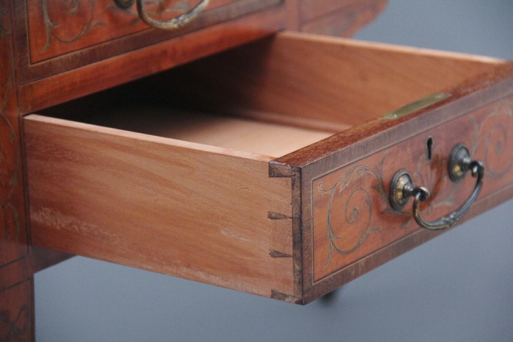 A 19th-century satinwood Carlton House writing desk featuring decorative marquetry, small drawers on a U-shaped superstructure, and tapered square legs with brass castors. View XVII