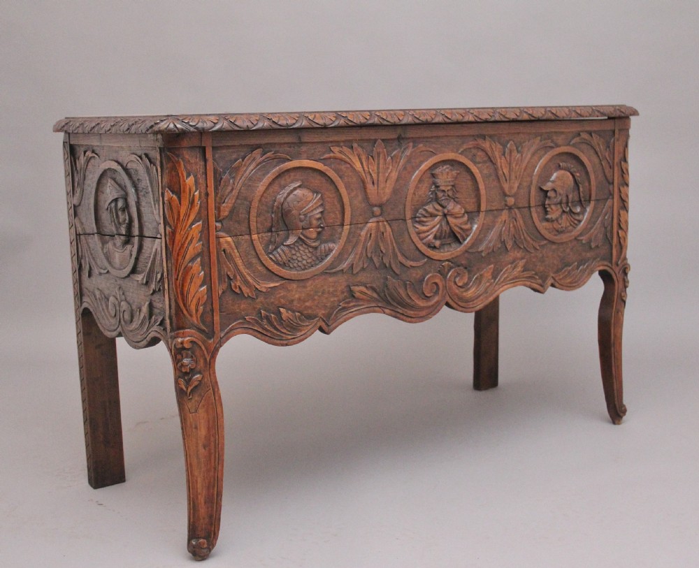 An early 19th-century French carved oak coffer featuring three carved profile medallions, acanthus leaf relief work, a scalloped apron, and cabriole legs. View II