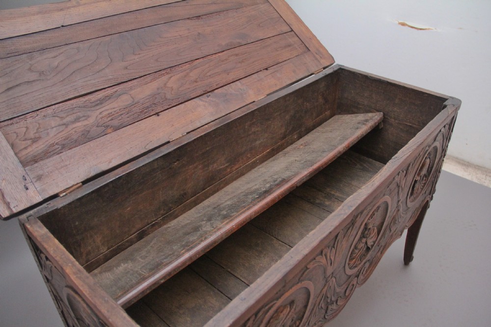 An early 19th-century French carved oak coffer featuring three carved profile medallions, acanthus leaf relief work, a scalloped apron, and cabriole legs. View V