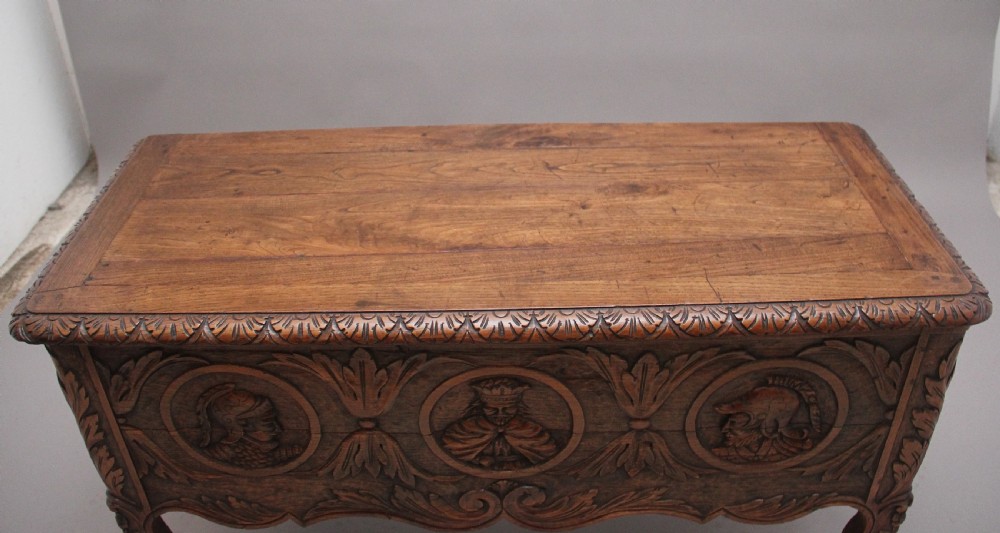 An early 19th-century French carved oak coffer featuring three carved profile medallions, acanthus leaf relief work, a scalloped apron, and cabriole legs. View VI