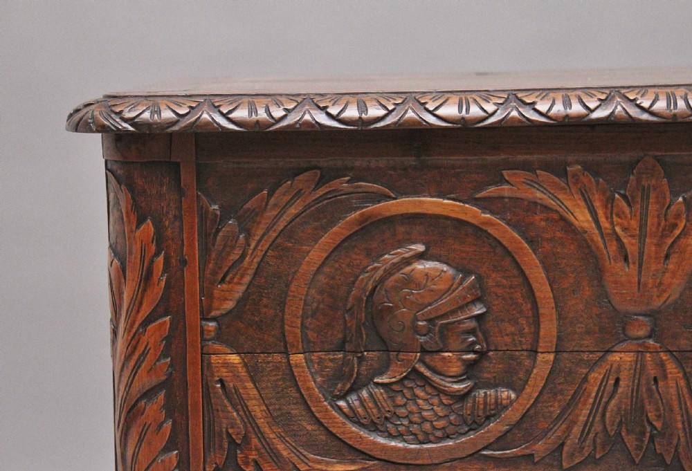 An early 19th-century French carved oak coffer featuring three carved profile medallions, acanthus leaf relief work, a scalloped apron, and cabriole legs. View VII