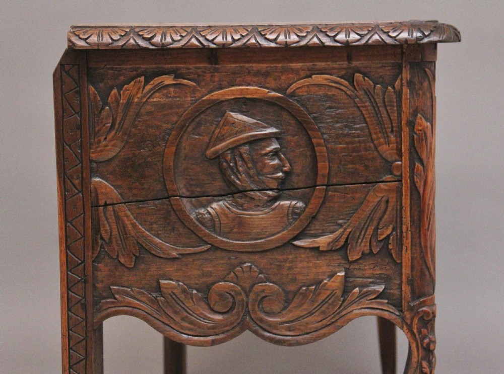 An early 19th-century French carved oak coffer featuring three carved profile medallions, acanthus leaf relief work, a scalloped apron, and cabriole legs. View XI