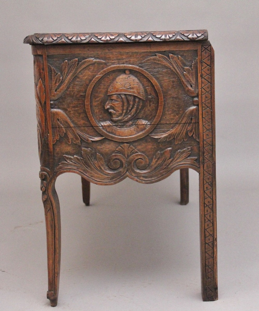 An early 19th-century French carved oak coffer featuring three carved profile medallions, acanthus leaf relief work, a scalloped apron, and cabriole legs. View XIII