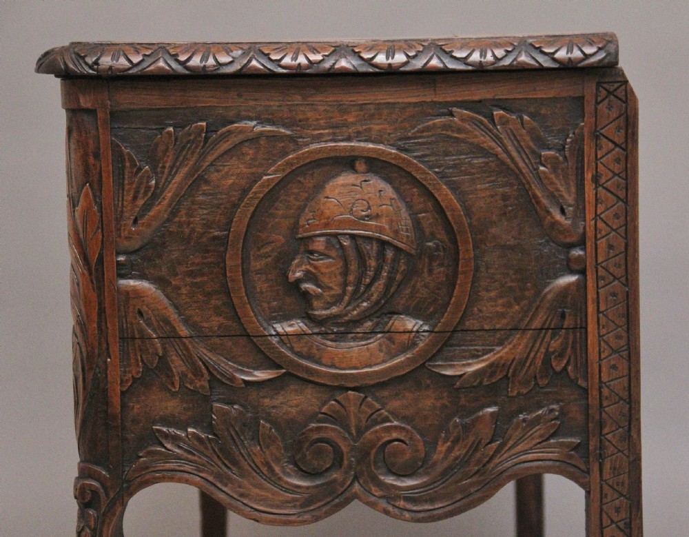 An early 19th-century French carved oak coffer featuring three carved profile medallions, acanthus leaf relief work, a scalloped apron, and cabriole legs. View XIV