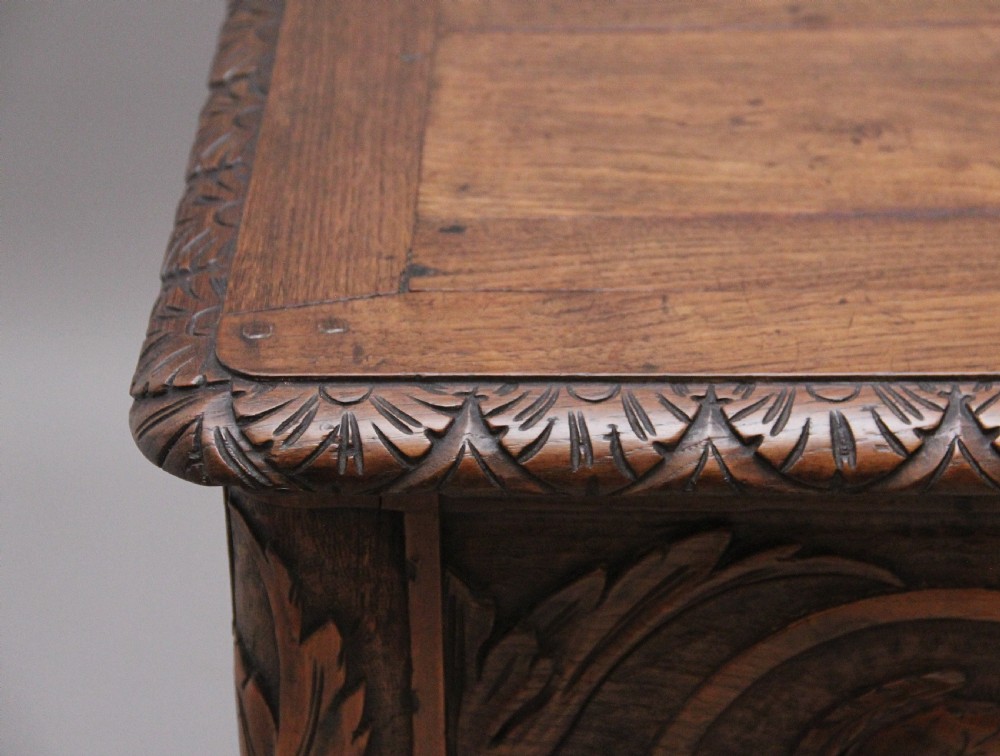 An early 19th-century French carved oak coffer featuring three carved profile medallions, acanthus leaf relief work, a scalloped apron, and cabriole legs. View XVI