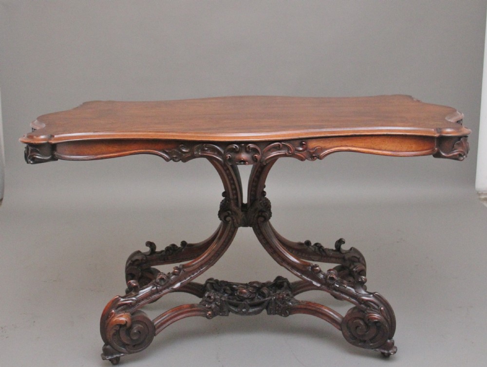 A 19th-century rosewood centre table featuring a serpentine top and carved C-scroll legs joined by a decorative stretcher.