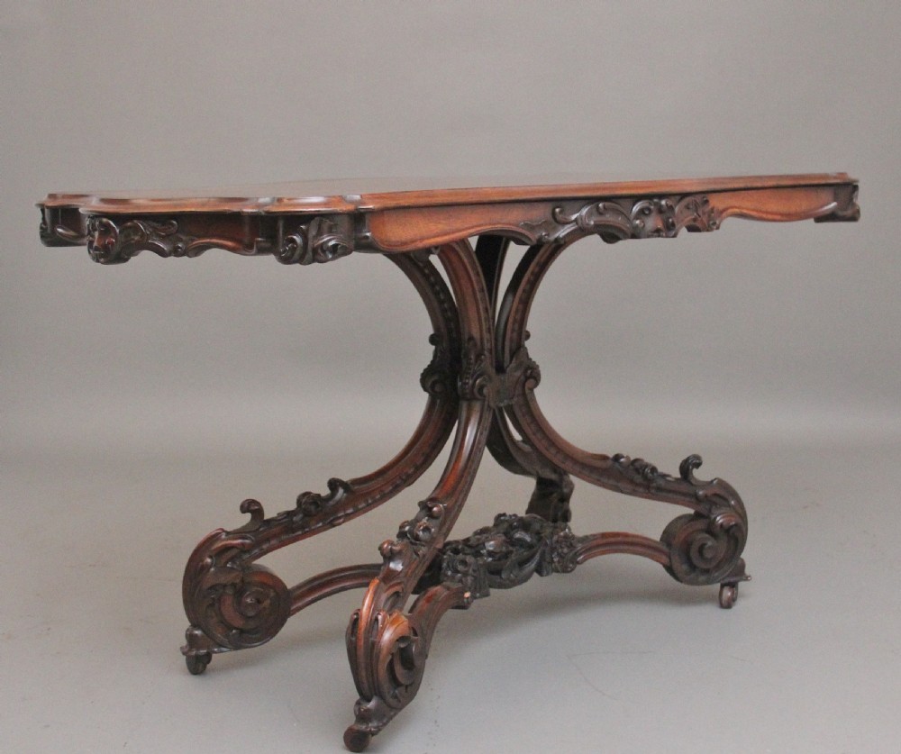 A 19th-century rosewood centre table featuring a serpentine top and carved C-scroll legs joined by a decorative stretcher. View V
