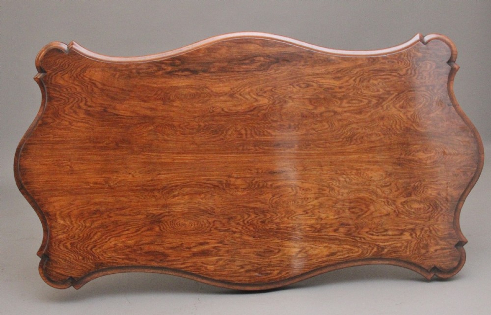 A 19th-century rosewood centre table featuring a serpentine top and carved C-scroll legs joined by a decorative stretcher. View VIII