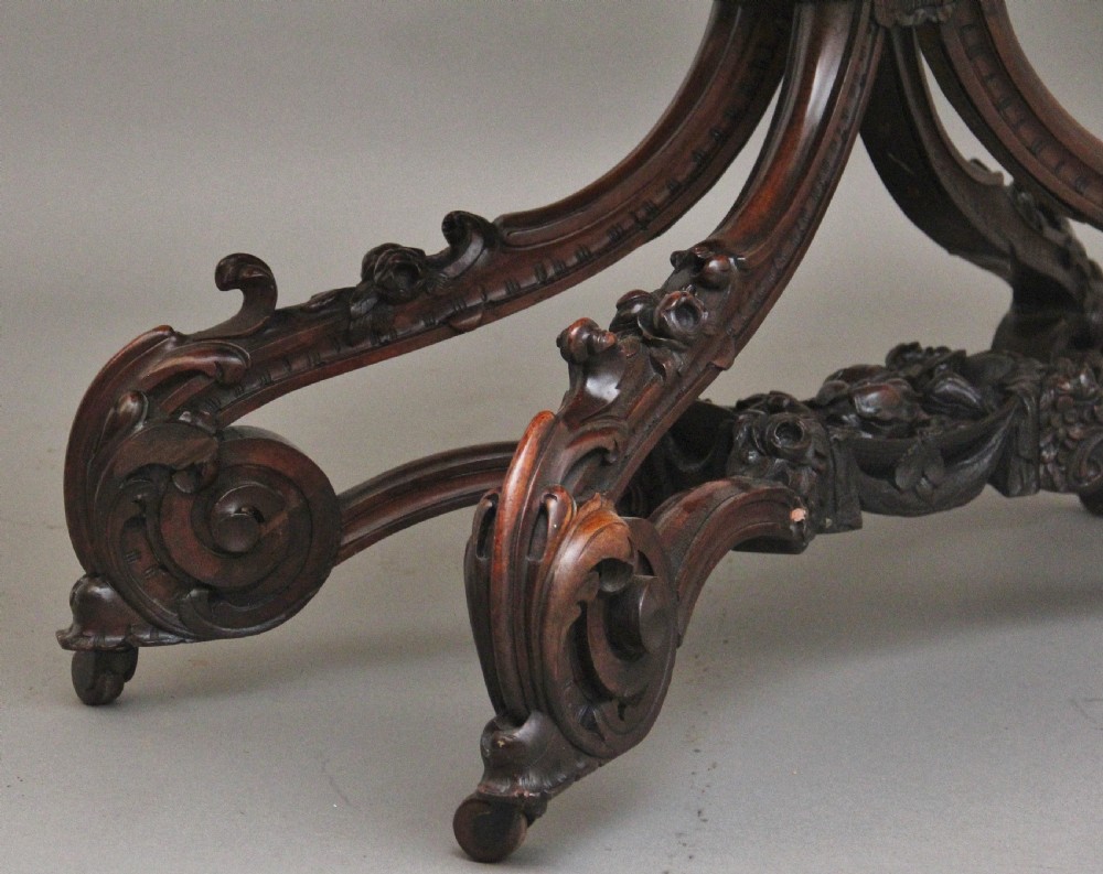A 19th-century rosewood centre table featuring a serpentine top and carved C-scroll legs joined by a decorative stretcher. View XI