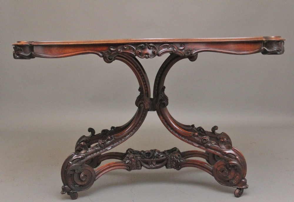 A 19th-century rosewood centre table featuring a serpentine top and carved C-scroll legs joined by a decorative stretcher. View XII