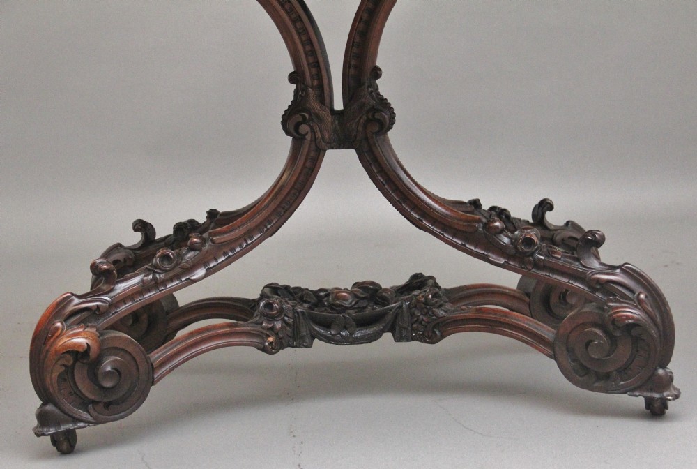 A 19th-century rosewood centre table featuring a serpentine top and carved C-scroll legs joined by a decorative stretcher. View XIII
