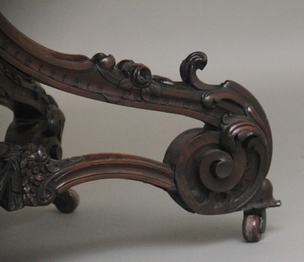 A 19th-century rosewood centre table featuring a serpentine top and carved C-scroll legs joined by a decorative stretcher. View XIV