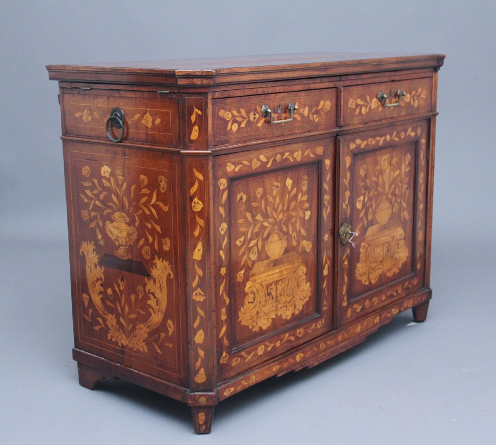 An early 19th-century Dutch travelling cabinet featuring floral fruitwood marquetry inlays, two upper drawers, two panelled doors, and side drop handles.