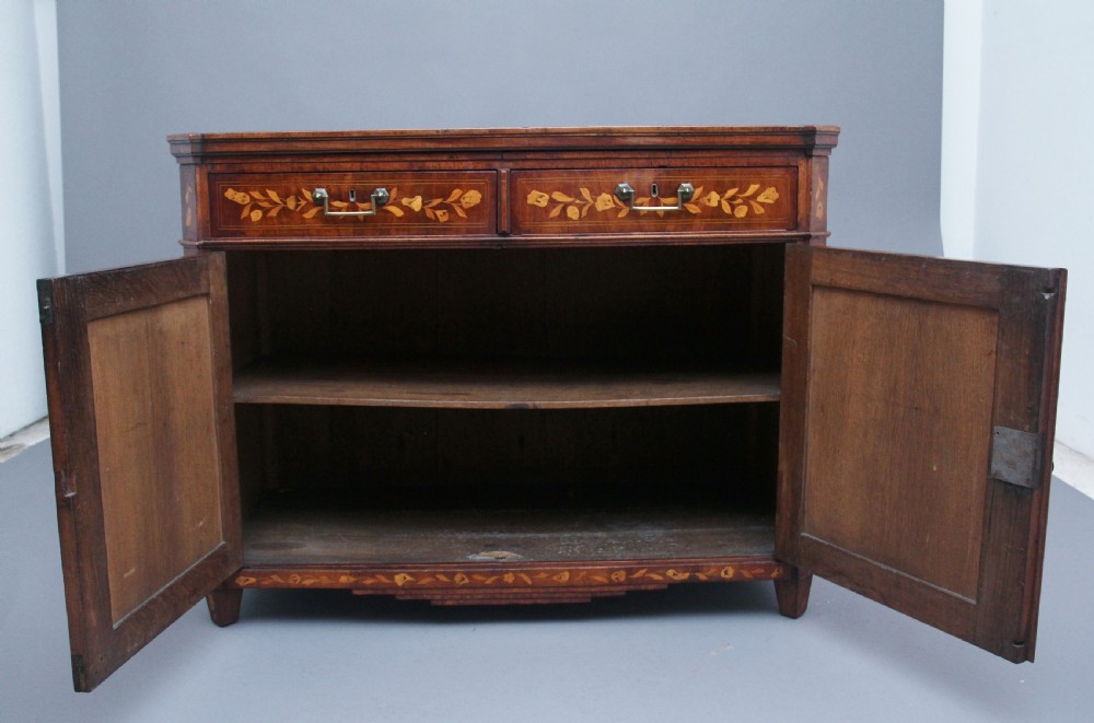 An early 19th-century Dutch travelling cabinet featuring floral fruitwood marquetry inlays, two upper drawers, two panelled doors, and side drop handles. View V
