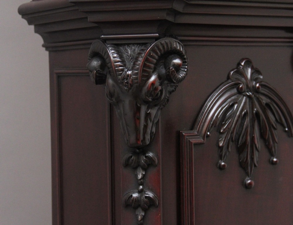 An early 20th-century carved dark mahogany longcase clock featuring an ornate pediment, carved trunk door, and etched brass dial. View XV