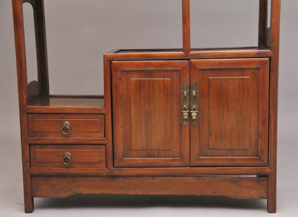 An early 20th-century Chinese hardwood duobaoge cabinet featuring asymmetrical open shelving, geometric side cut-outs, and lower drawers with brass hardware. View IV