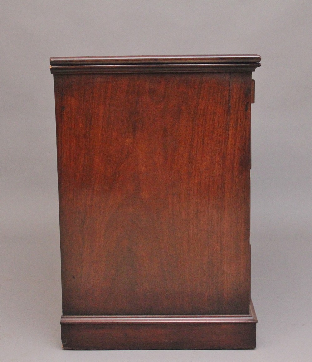 An early 19th-century mahogany kneehole desk with a dark leather writing top, multiple side drawers with circular brass ring handles, and a central recessed cupboard door. View VI