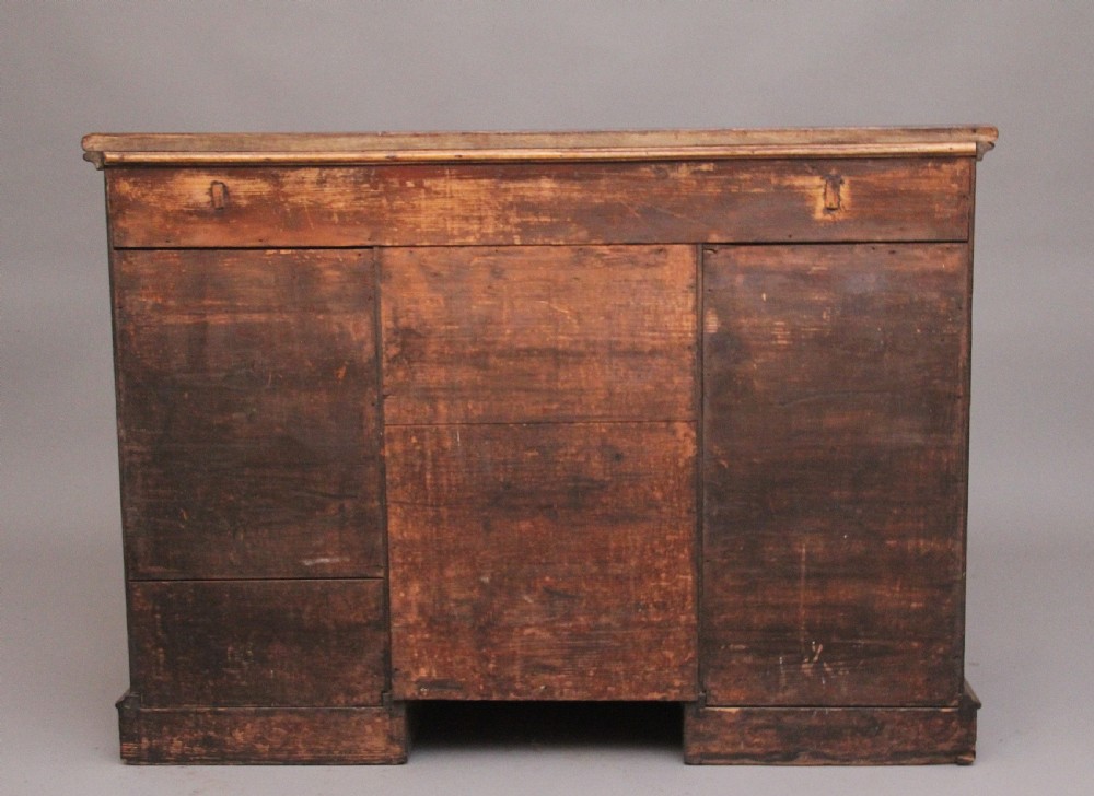 An early 19th-century mahogany kneehole desk with a dark leather writing top, multiple side drawers with circular brass ring handles, and a central recessed cupboard door. View VII