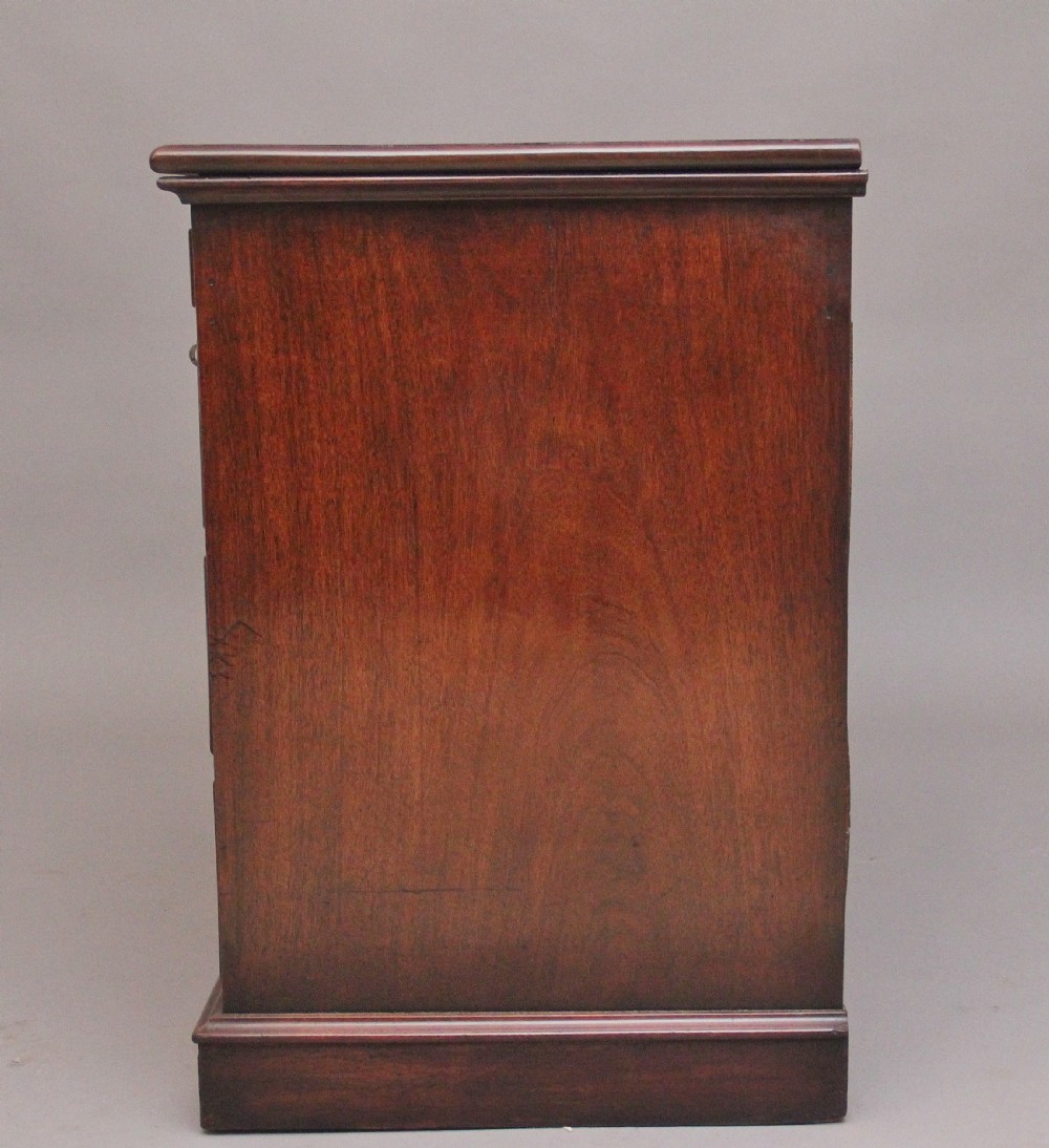 An early 19th-century mahogany kneehole desk with a dark leather writing top, multiple side drawers with circular brass ring handles, and a central recessed cupboard door. View VIII