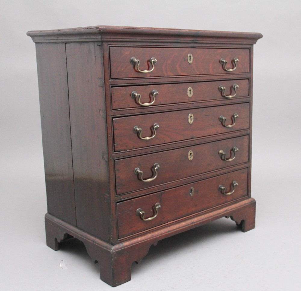 An 18th-century Georgian dark oak chest of drawers featuring five horizontal graduated drawers with brass swan-neck handles, brass escutcheons, and bracket feet. View III