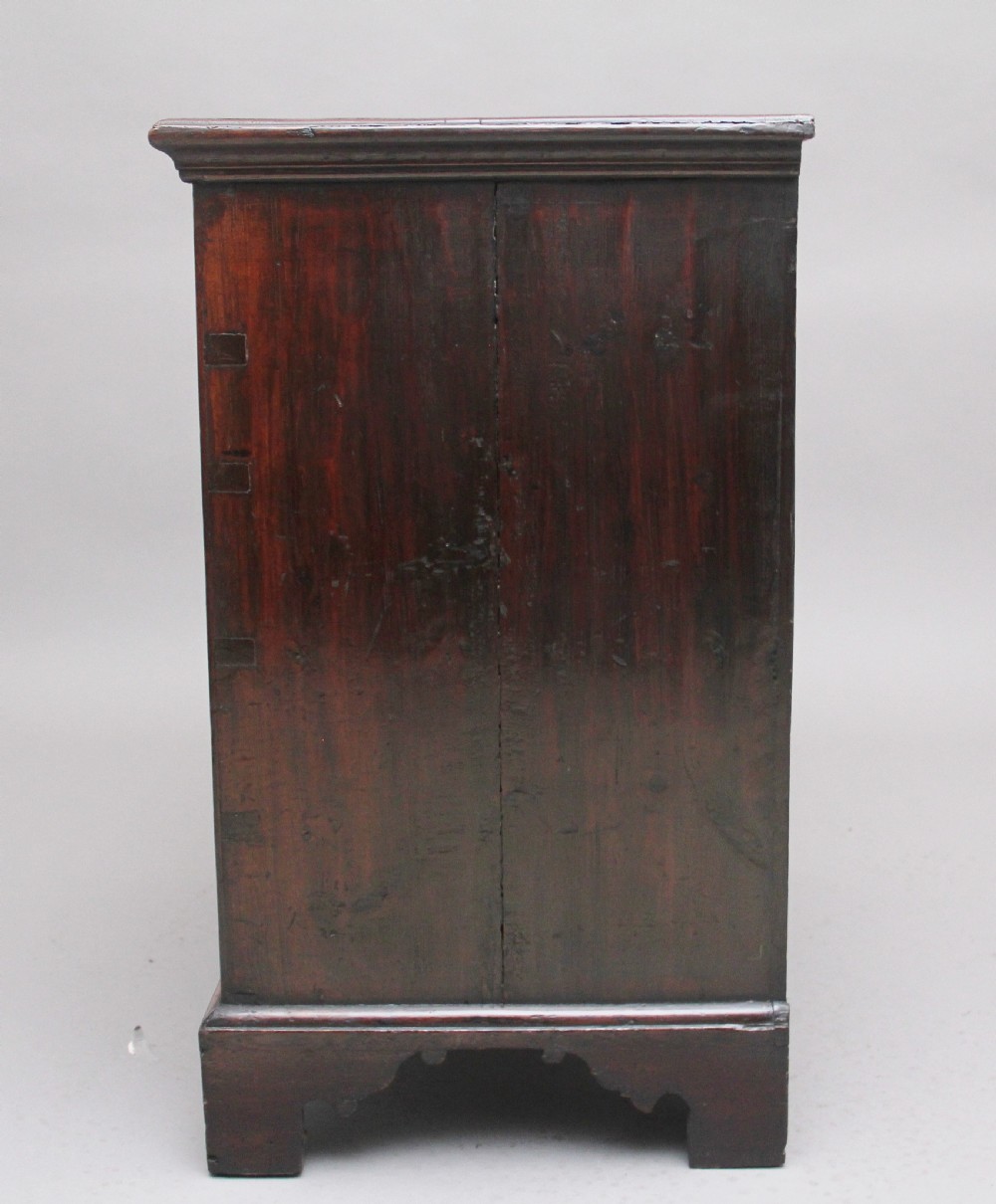 An 18th-century Georgian dark oak chest of drawers featuring five horizontal graduated drawers with brass swan-neck handles, brass escutcheons, and bracket feet. View X
