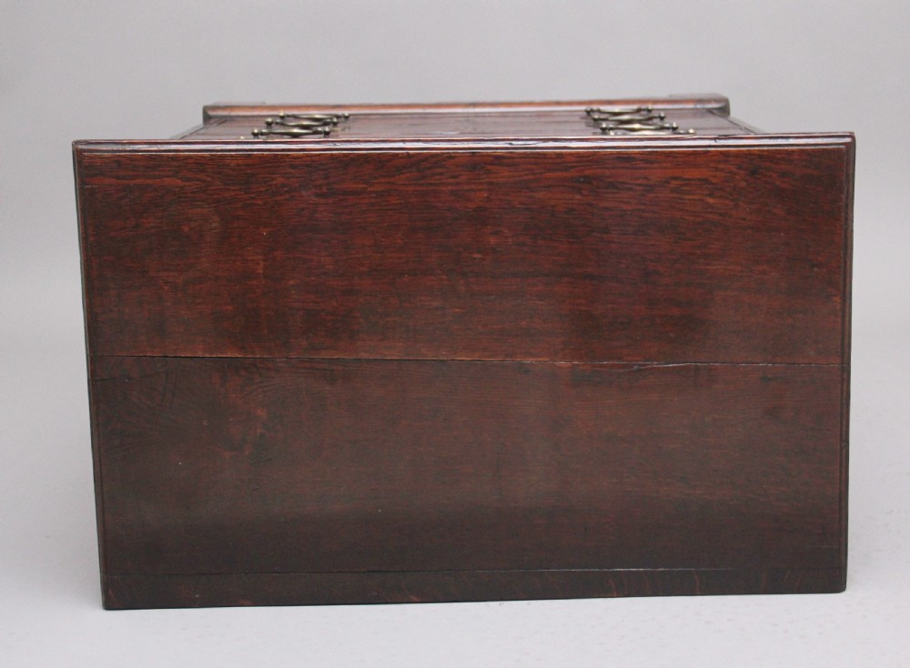 An 18th-century Georgian dark oak chest of drawers featuring five horizontal graduated drawers with brass swan-neck handles, brass escutcheons, and bracket feet. View XI