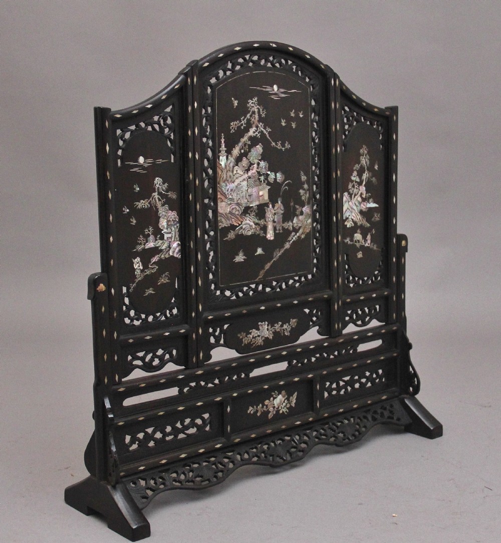 A 19th-century Chinese dark hardwood triptych table screen set with carved openwork borders and detailed mother-of-pearl landscape inlays. View II